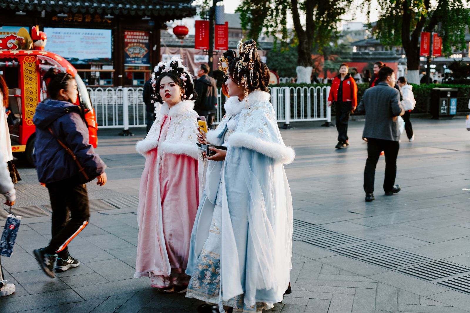 People in traditional attire strolling through a vibrant Nanjing street in autumn